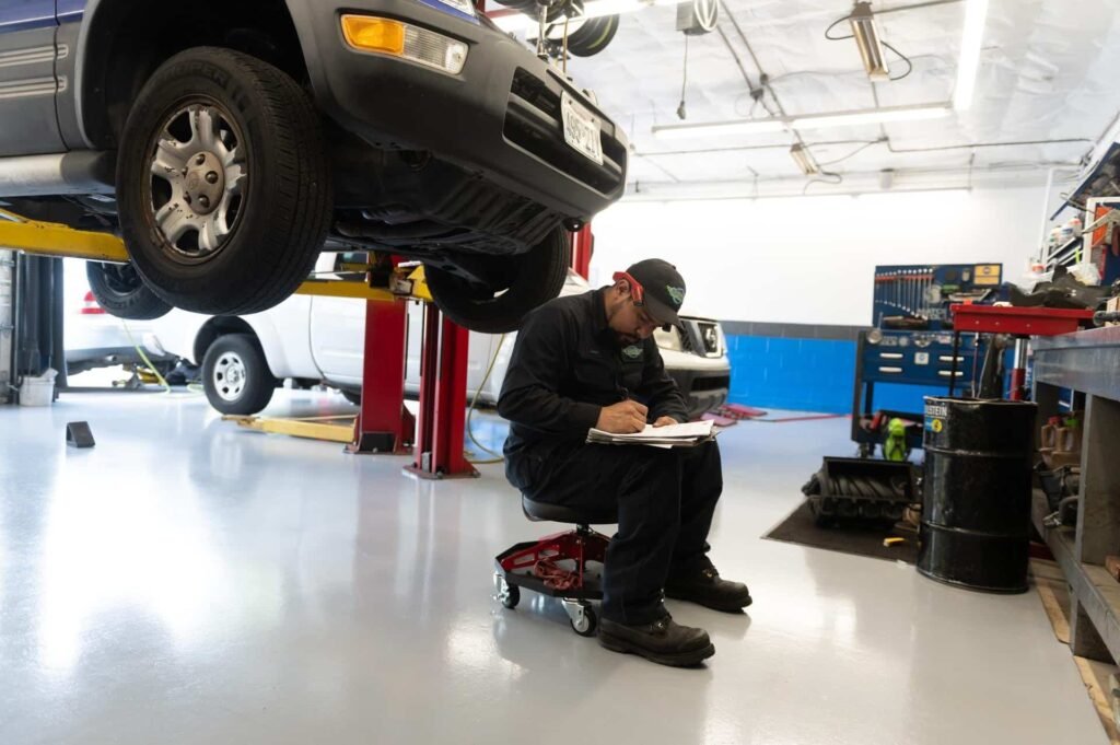 A technician recording inspection findings beneath a lifted SUV at Chuck's Auto Repair