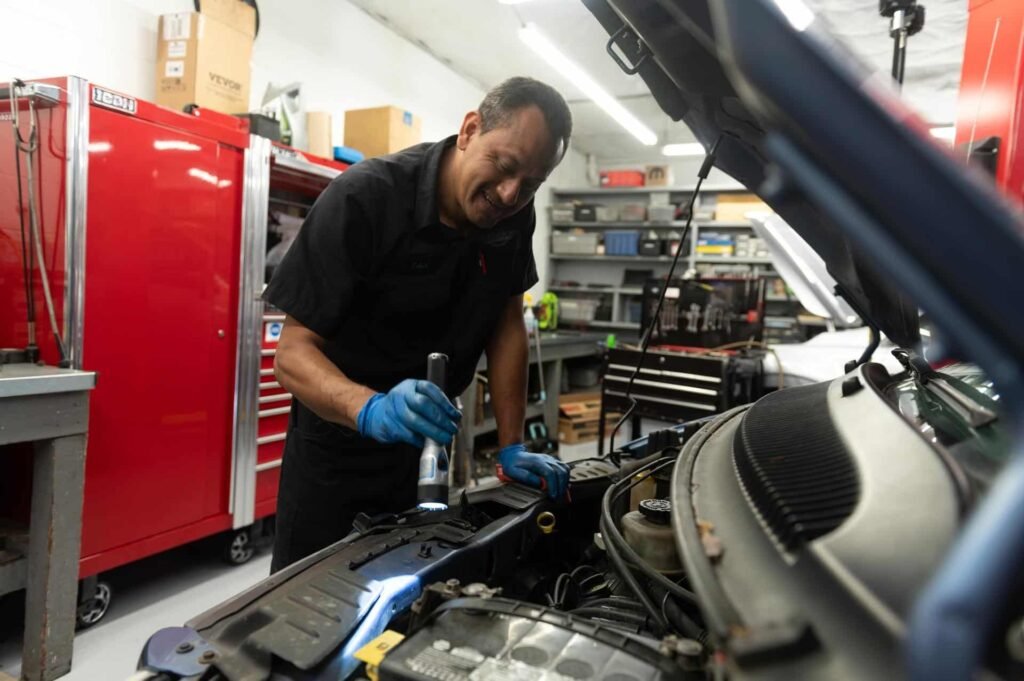 A technician using a flashlight to inspect an engine at Chuck's Auto Repair