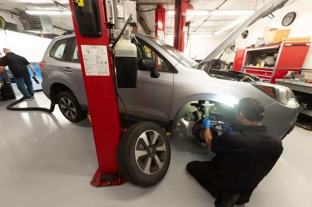 A technician performing front brake repair on a Subaru Forester at Chuck's Auto Repair
