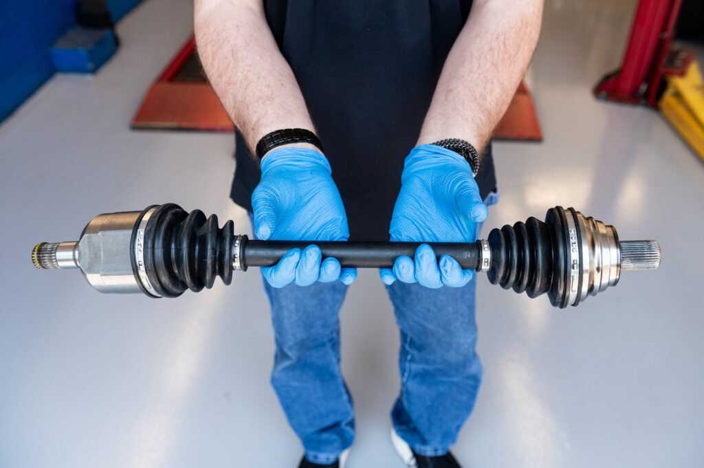 Technician holding a new cv axle assembly (new boots and joints, ready to install) before installation during CV axle replacement at Chuck's Auto Repair in North Seattle
