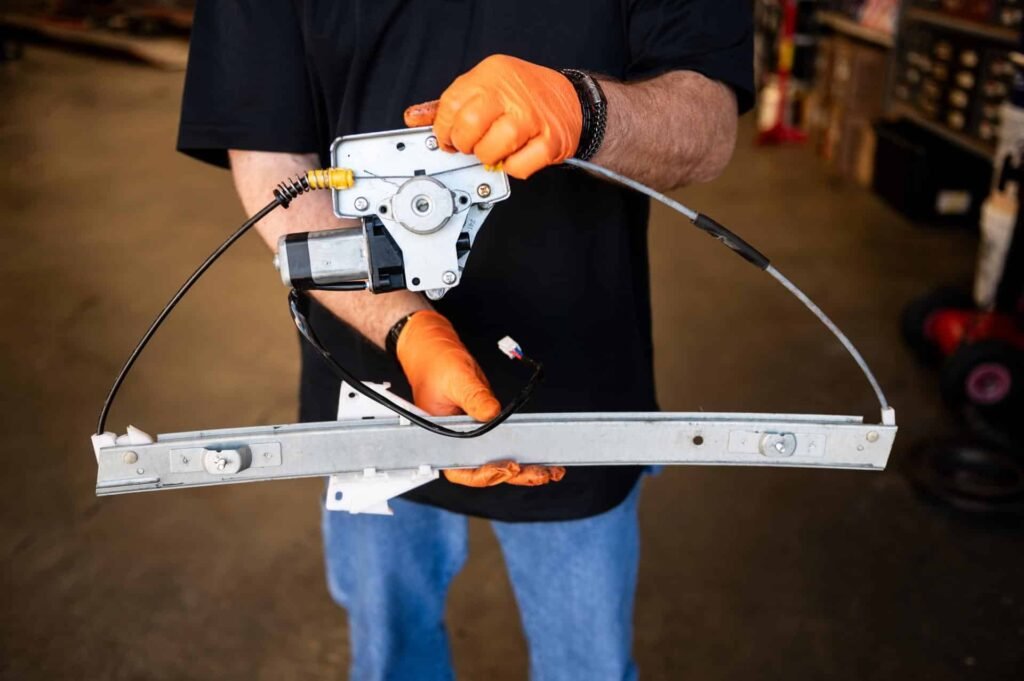 Technician holding a power window regulator with motor — failed, replaced during power window repair at Chuck's Auto Repair in North Seattle