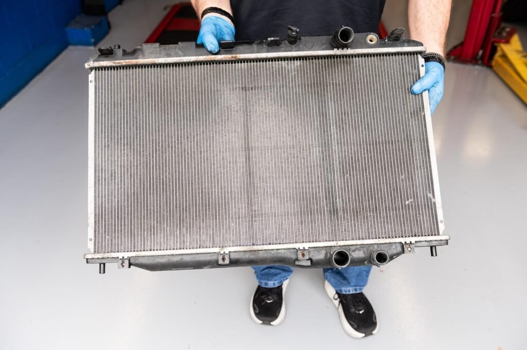 Technician holding a radiator — leaking, replaced during radiator replacement at Chuck's Auto Repair in North Seattle