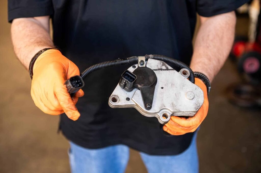 Technician holding a transfer case shift actuator — failed, replaced during 4WD repair at Chuck's Auto Repair in North Seattle