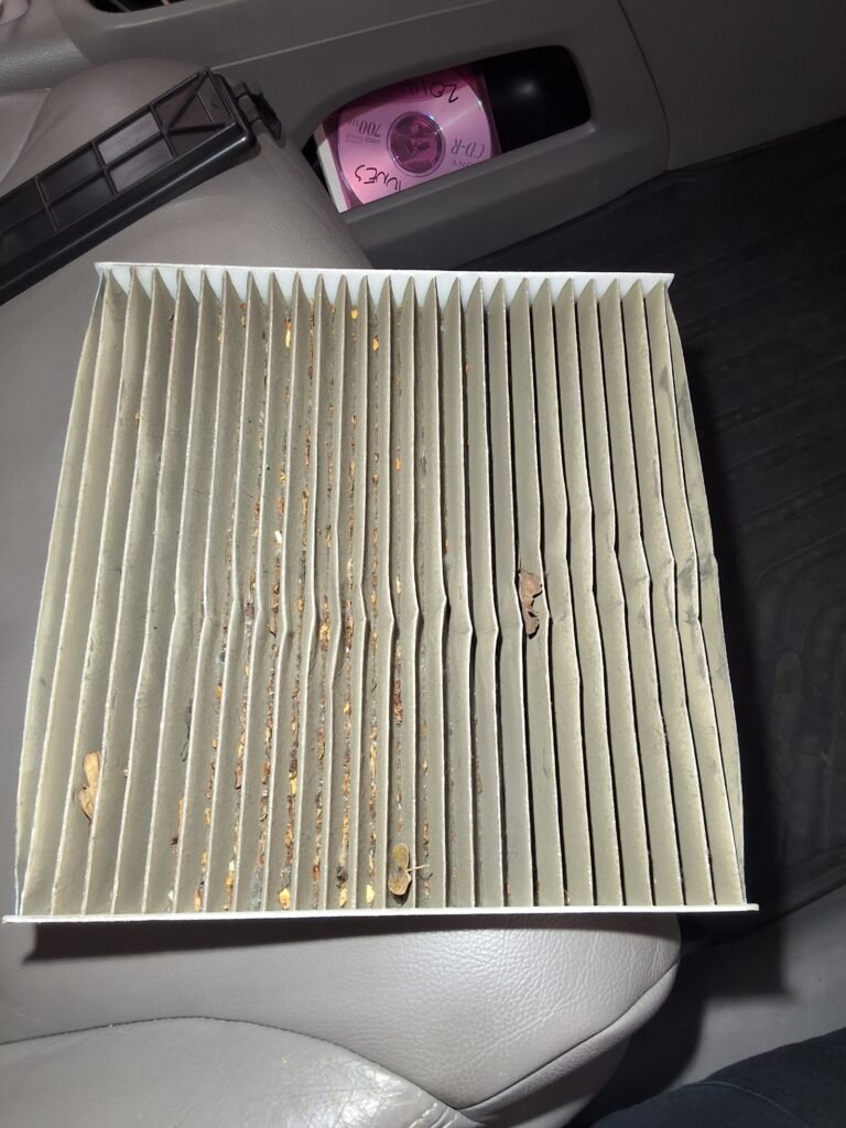Dirty cabin air filter removed from a Honda CR-V with debris trapped between the filter pleats.