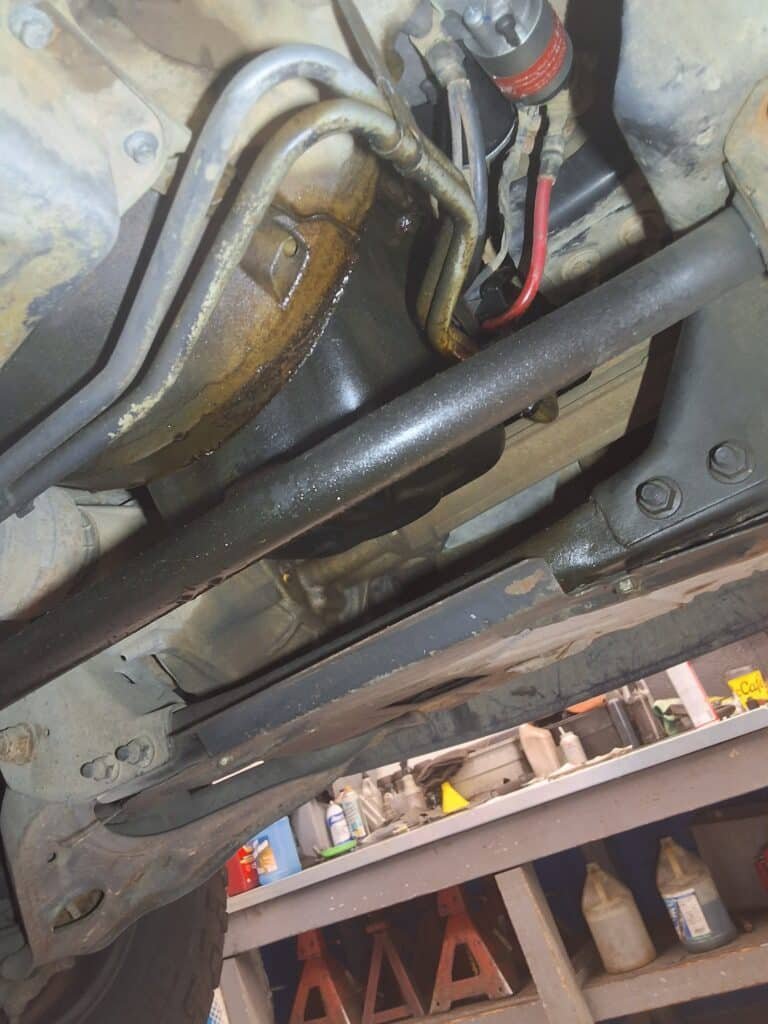 Oil residue visible around the lower engine and oil pan area underneath a Ford F-150.