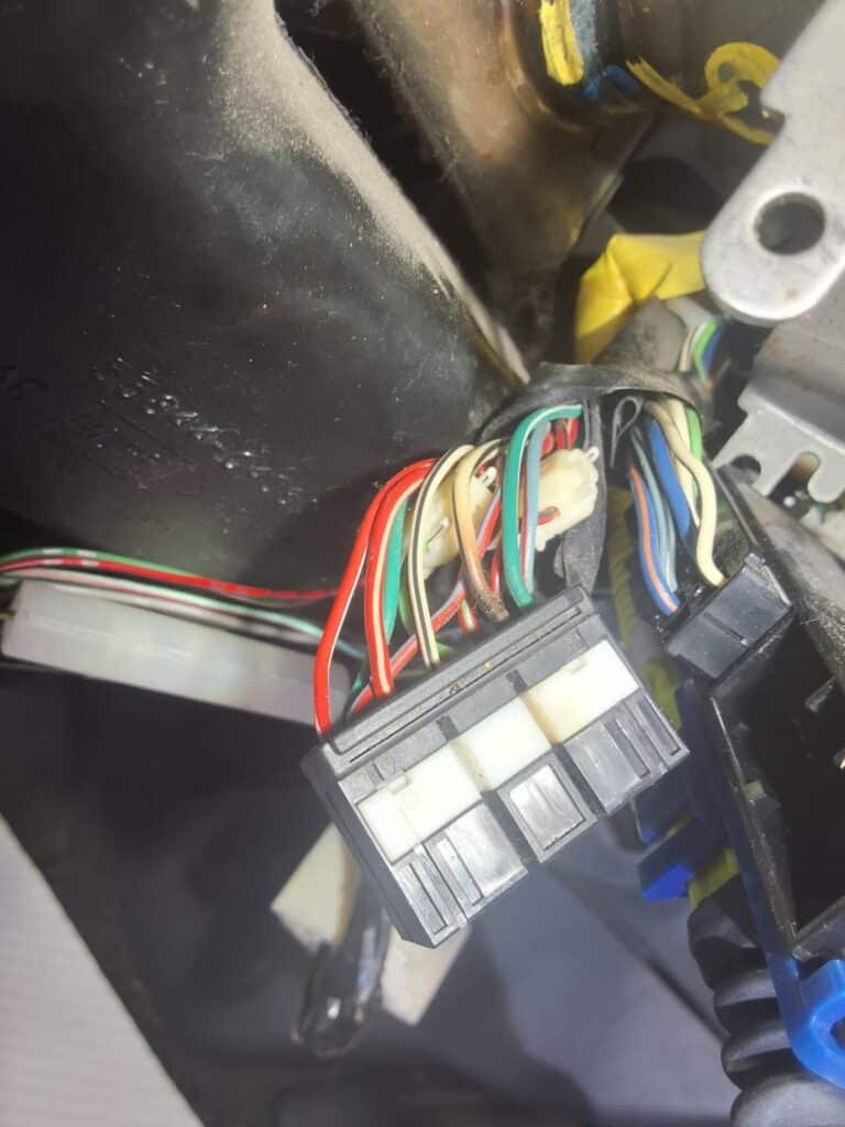 Damaged wiring under the steering column of an older Toyota Tacoma during electrical diagnosis.